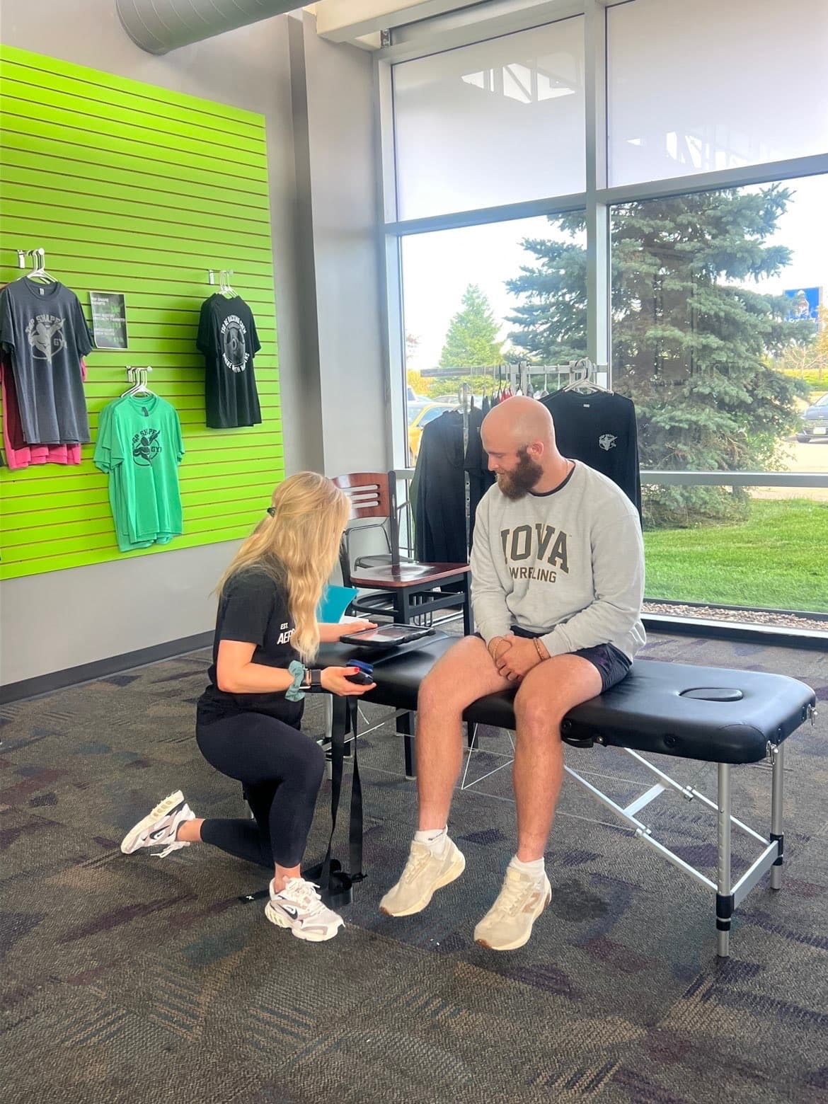 Aero Performance physical therapist performing a hands-on orthopedic evaluation of a patient's knee while he sits on a treatment table in the Coralville, Iowa clinic